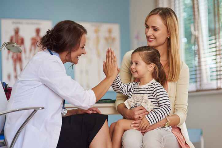Family medicine doctor giving a high-five to a young patient as part of compassionate wellness services in Lansing.