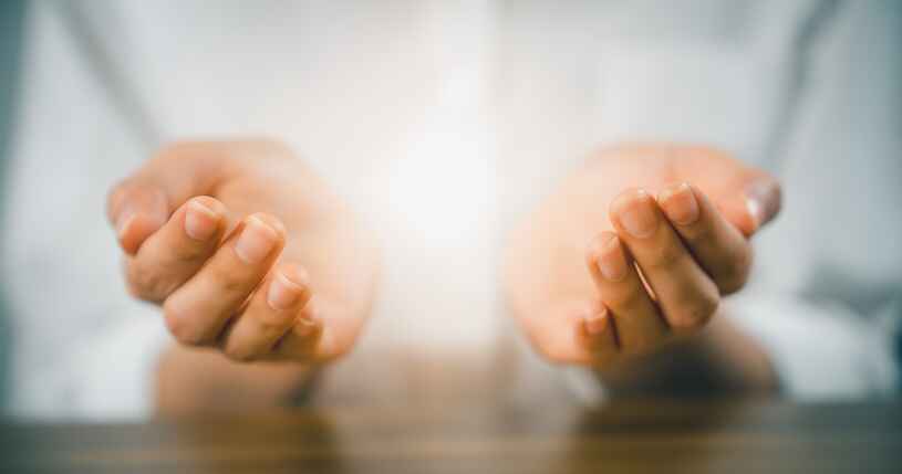 Open hands with soft glowing light representing spiritual healing offered through wellness services in Lansing.