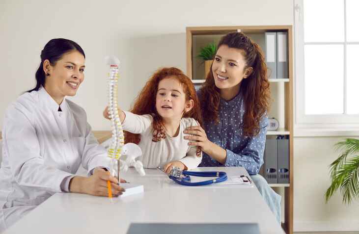 Pediatric chiropractor showing spine model to child
